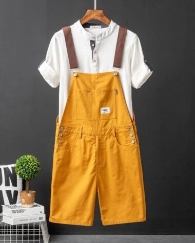 Une salopette orange pendue sur un cintre avec un t-shirt blanc sur un fond noir.