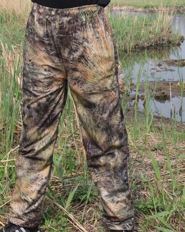 Photo d'une salopette pantalon de chasse portée par un homme avec fond de végétation