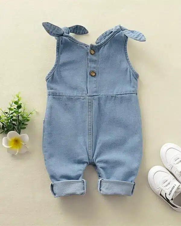 Salopette bleue jean pour bébé fille avec petits noeuds aux épaules et baskets blanches