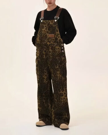 Salopette leopard oversize marron et vert kaki, avec une poche ventrale et deux latérales, portée par une jeune femme sur fond beige.