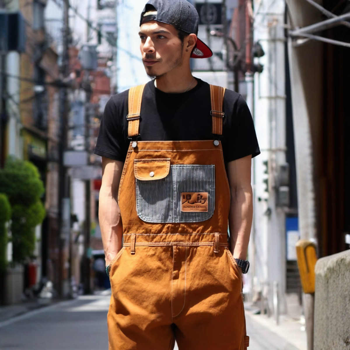 Salopette orange style urbain japonais 1 Salopette orange style urbain japonnais avec multipoches centrales, portée avec un t-shirt noir par une jeune homme.