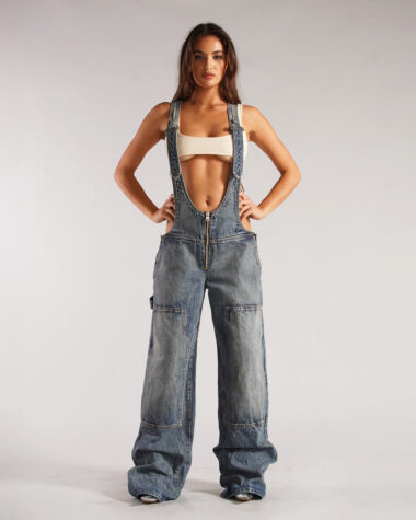 Salopette jean femme ultra-décolleté, sexy, denim brut, style iconique portée par une jeune femme vêtue d'une brassière.