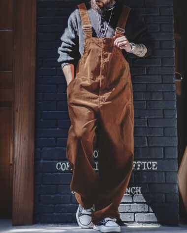 Salopette velour au charme rétro marron confortable portée par un jeune homme vêtu d'une chemise bleu en jean