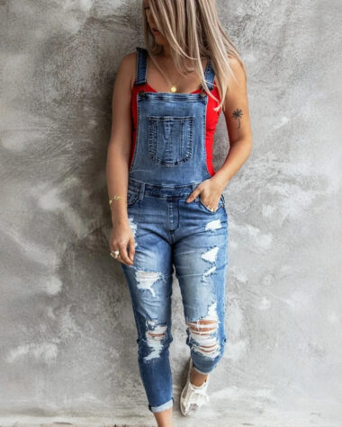 Salopette en jeans destroy bleu délavé porté par une jeune femme caucasienne blonde
