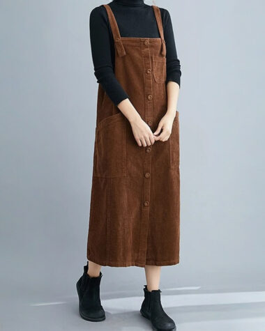 Robe salopette en velours mi-longue marron portée avec un col roulé par une jeune femme caucasienne