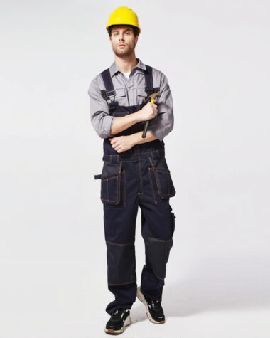 Salopette de travail homme haute performance en bleu jean portée par un travailleur de type caucasien avec un casque de chantier jaune