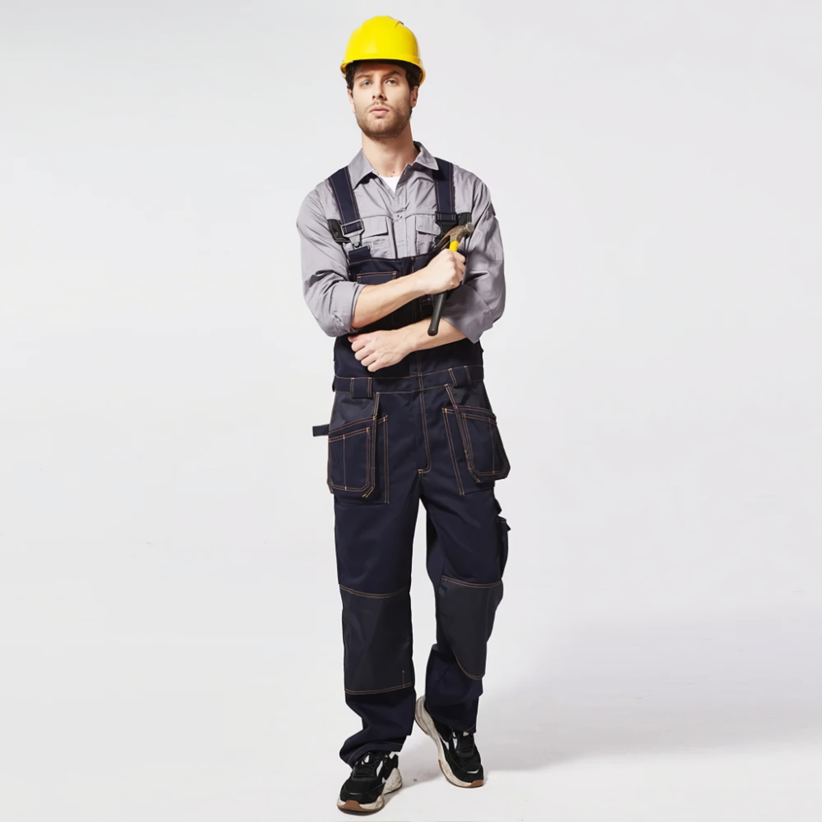 Salopette de travail homme haute performance en bleu jean portée par un travailleur de type caucasien avec un casque de chantier jaune